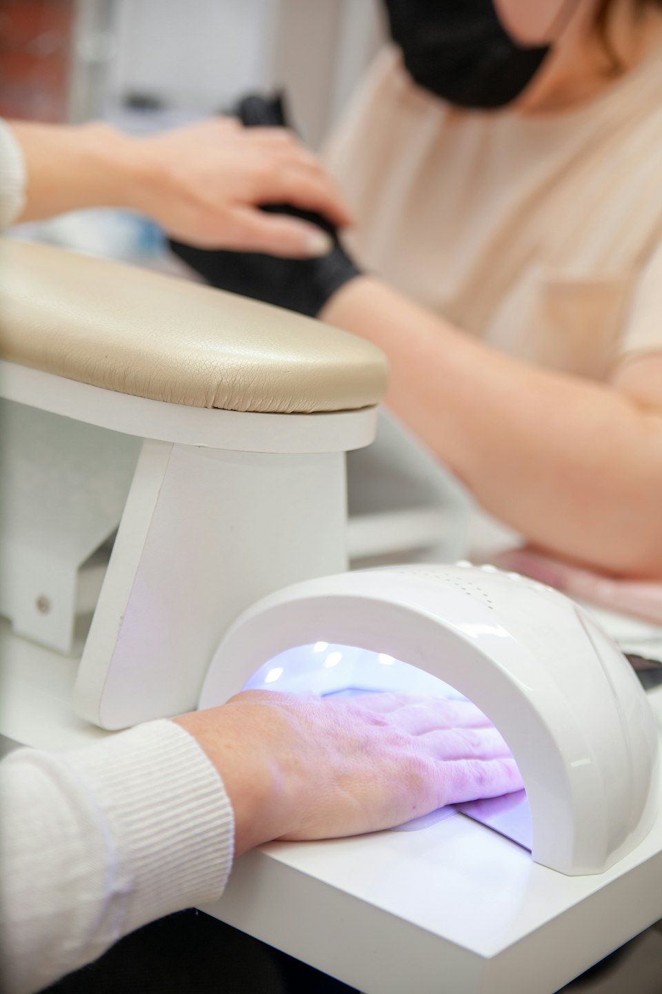 Manicurista che polimerizza lo smalto gel sotto una lampada UV.